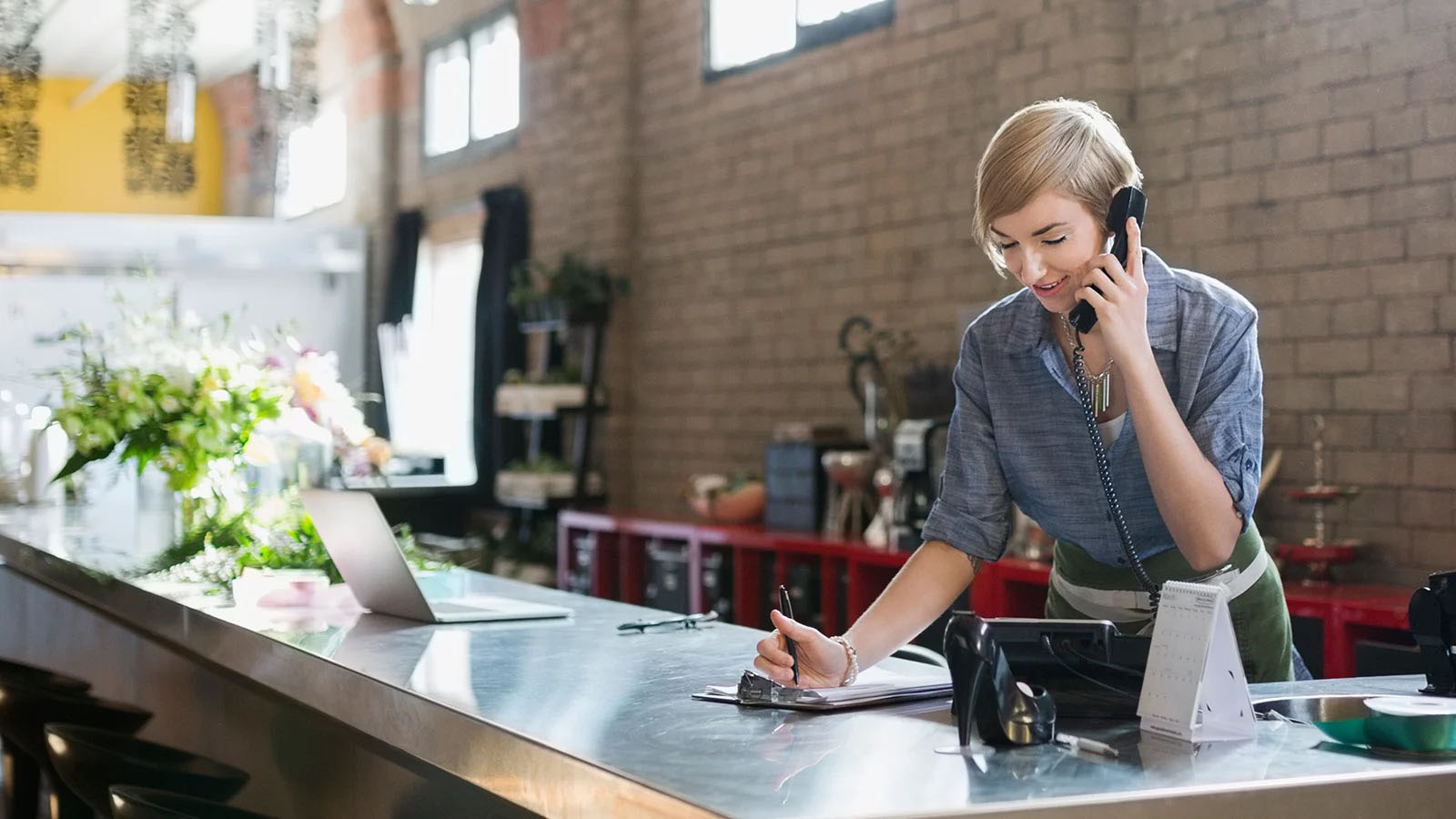 Retailer at counter making phone call.