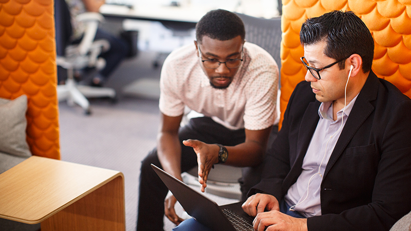 Two seated men discussing laptop display. Two seated men discussing laptop display.