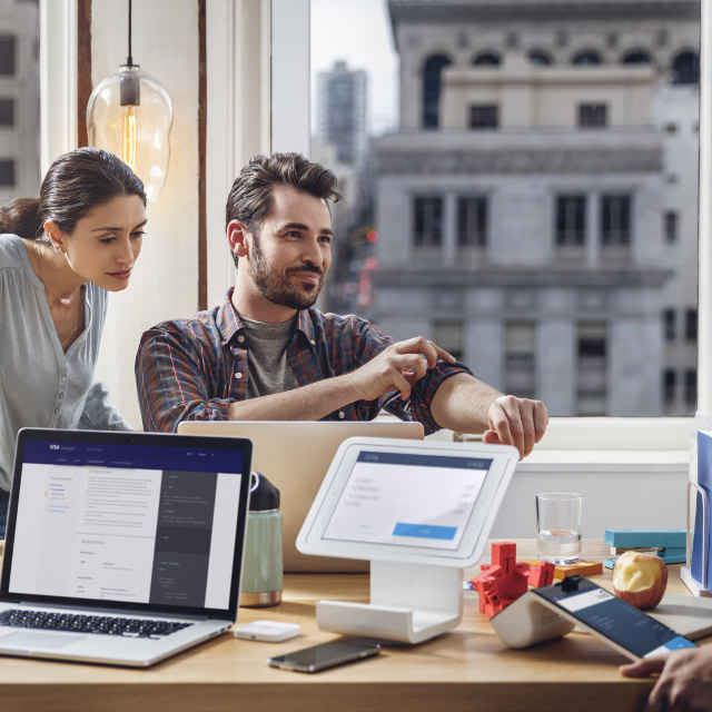 People around a desk with laptops and tablets open.