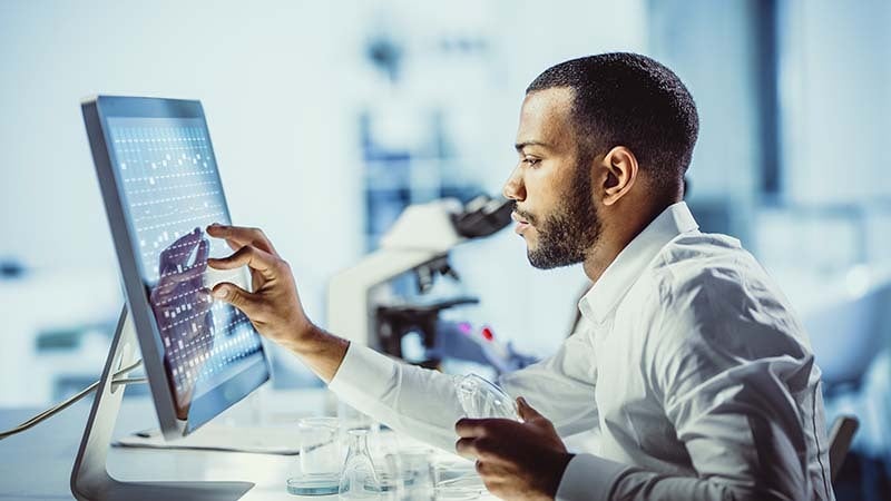 Imagem exibe homem trabalhando em computador com tela sensível ao toque. 