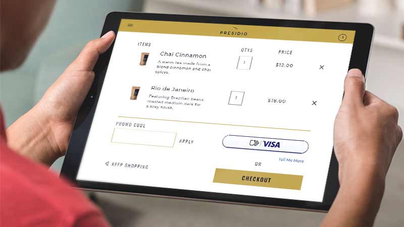 A woman holds a tablet that displays the new checkout experience.